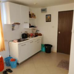 Compact kitchen with white cabinetry and tile flooring