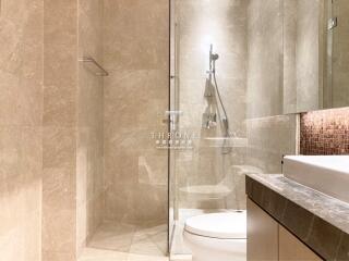 Modern bathroom with glass shower booth, elegant basin, and marble finishes