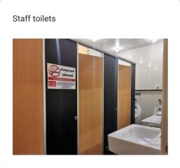Staff bathroom interior with multiple stalls and sinks