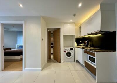 Modern kitchen with connected laundry space and view into bedroom