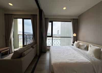 Modern bedroom with a large bed and expansive city view through floor-to-ceiling windows
