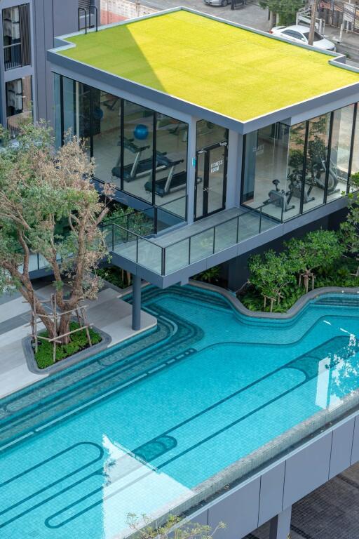 Modern two-story building with glass walls, an outdoor swimming pool, and a green rooftop