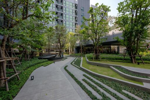 Modern residential building exterior with landscaped garden and walking paths