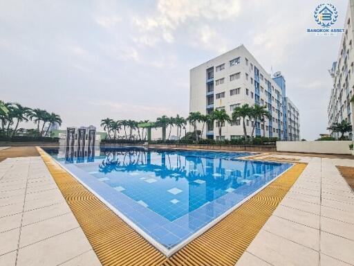 Communal swimming pool with surrounding lounging area in a residential complex