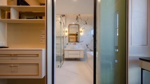 Modern bathroom with glass door, marble walls, and vanity area