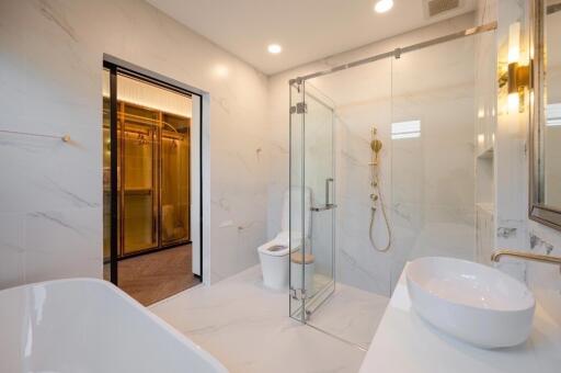 Modern bathroom with white marble tiles, walk-in shower, and gold fixtures