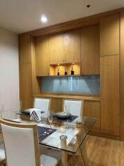 Modern dining area with wooden cabinets and glass table