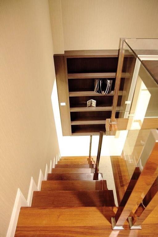 Modern wooden staircase with glass balustrade leading to a lower level