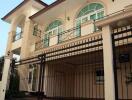 Front view of a two-story residential house with a balcony and gated entrance