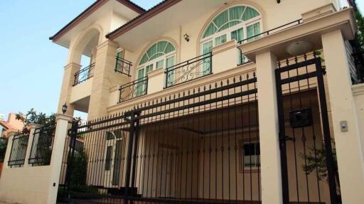 Front view of a two-story residential house with a balcony and gated entrance