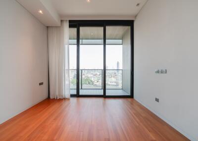 Spacious bedroom with hardwood floors and a large window with city view