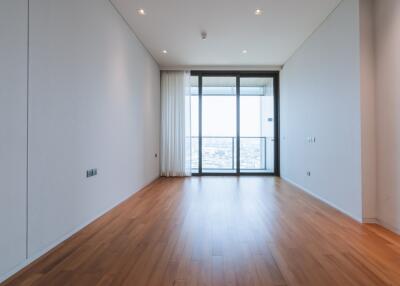 Spacious, unoccupied bedroom with hardwood floors and a large window with a city view