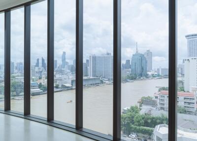 Spacious living room with floor-to-ceiling windows offering a panoramic city and river view