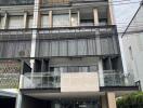 Modern multi-story residential building with balconies and covered parking area