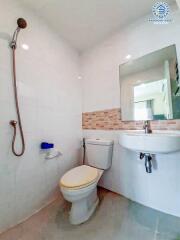 Modern bathroom with wall-mounted sink, glass shower, and brick accent wall