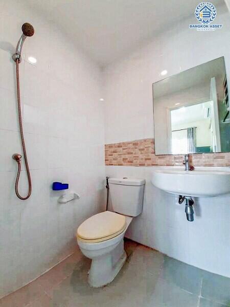 Modern bathroom with wall-mounted sink, glass shower, and brick accent wall