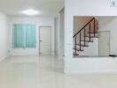 Spacious white living room with stairs and glossy tiled floor