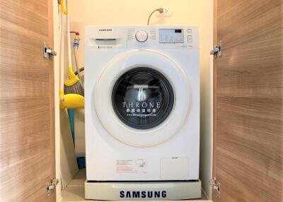 Compact laundry area with modern Samsung washing machine enclosed in wooden cabinetry
