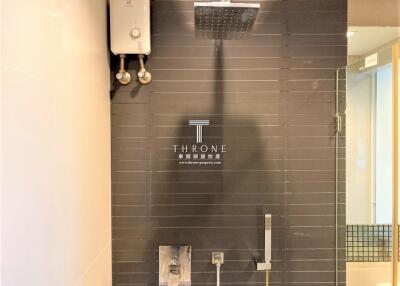 Modern bathroom with overhead shower and dark tiles