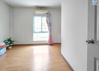 Bright and empty bedroom with wooden flooring and a window