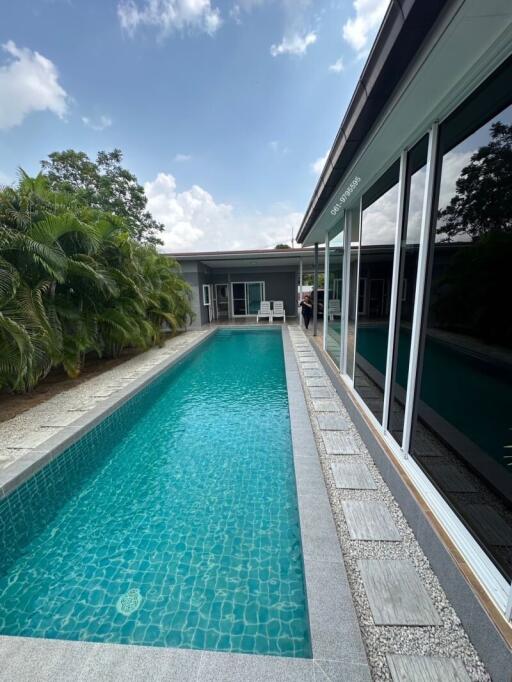 Backyard with swimming pool adjacent to a modern house with large windows