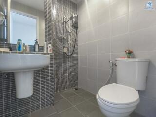 Modern bathroom with wall-mounted sink, toilet, and shower area