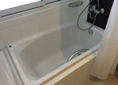 Clean white bathtub with tiled walls and a shower fixture