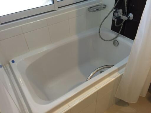 Clean white bathtub with tiled walls and a shower fixture