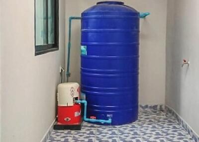 Compact utility area with blue water storage tank and patterned flooring