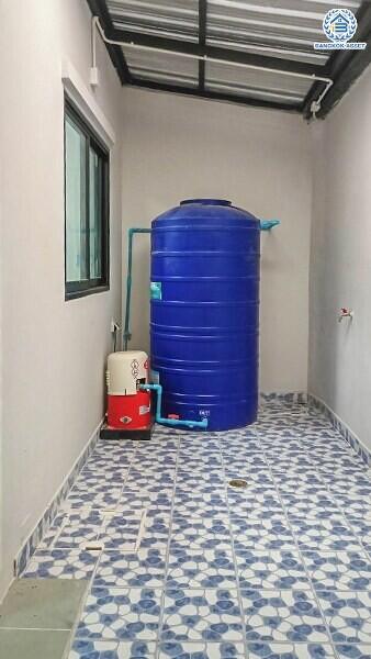 Compact utility area with blue water storage tank and patterned flooring