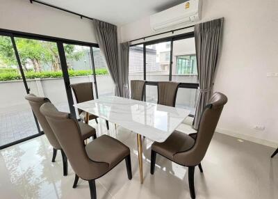 Modern dining area with large glass table and garden view through sliding glass doors