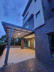 Modern building exterior with covered entrance and parking area at twilight