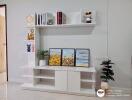 Modern white living room interior with decorative shelving, art pieces, and plants