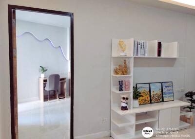 Modern living room interior with white shelving unit and decorations, view into dining area