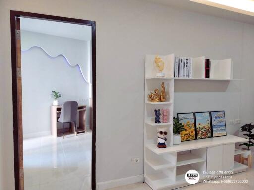 Modern living room interior with white shelving unit and decorations, view into dining area