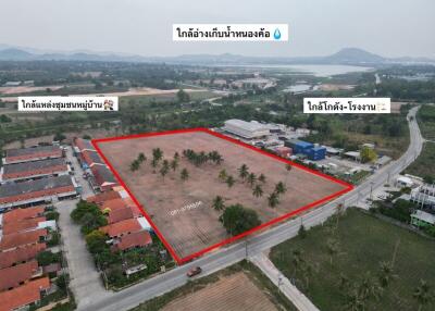 Aerial view of a spacious land plot for sale with surrounding palm trees and nearby residential and industrial areas