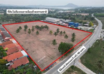 Aerial view of a large vacant land plot for sale bordered by a road and nearby buildings