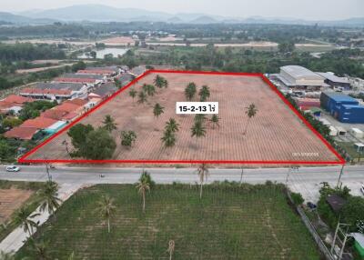 Aerial view of a vacant land plot outlined in red with palm trees and nearby residential area