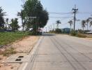 Paved road leading to properties with clear sky and greenery