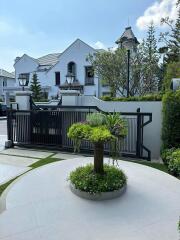 Elegant white townhouse exterior with manicured front yard and secure gate
