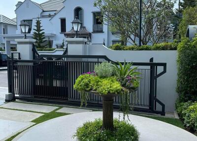 Elegant white townhouse exterior with manicured front yard and secure gate