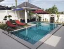 Private swimming pool with sun loungers and patio area in a residential property