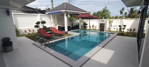 Private swimming pool with sun loungers and patio area in a residential property