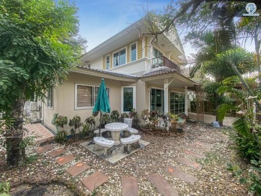 Front view of a two-story house with garden and outdoor sitting area