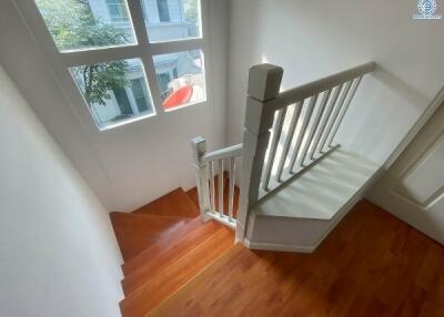 Bright staircase with wooden floors and white banister inside a house