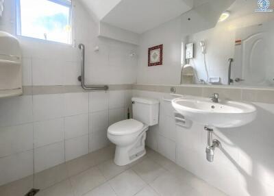 Clean white tiled bathroom with safety grab bars and under-sink storage