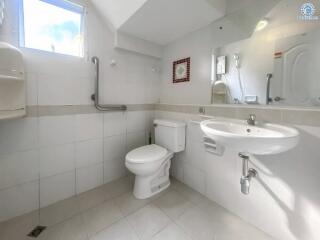 Clean white tiled bathroom with safety grab bars and under-sink storage