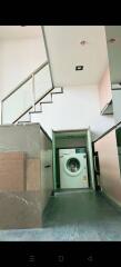 Compact laundry room with a washing machine under the stairs