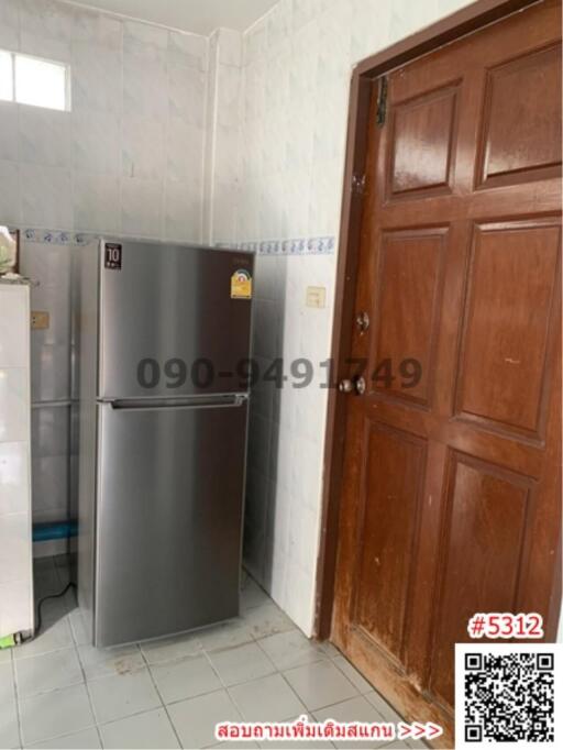 Compact kitchen space with large refrigerator and wooden door