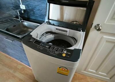 Top-loading washing machine in a small laundry area next to kitchen sink